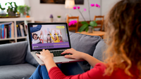 Teacher sitting on the couch taking online training on a laptop